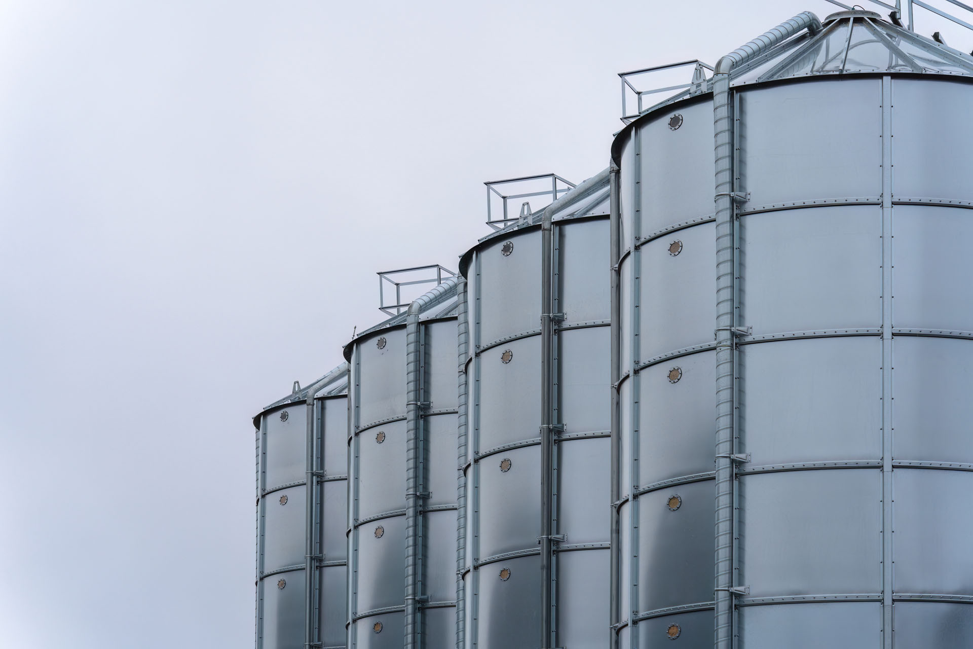 Stainless,Steel,Industrial,Silos,With,Overcast,Sky,Background.